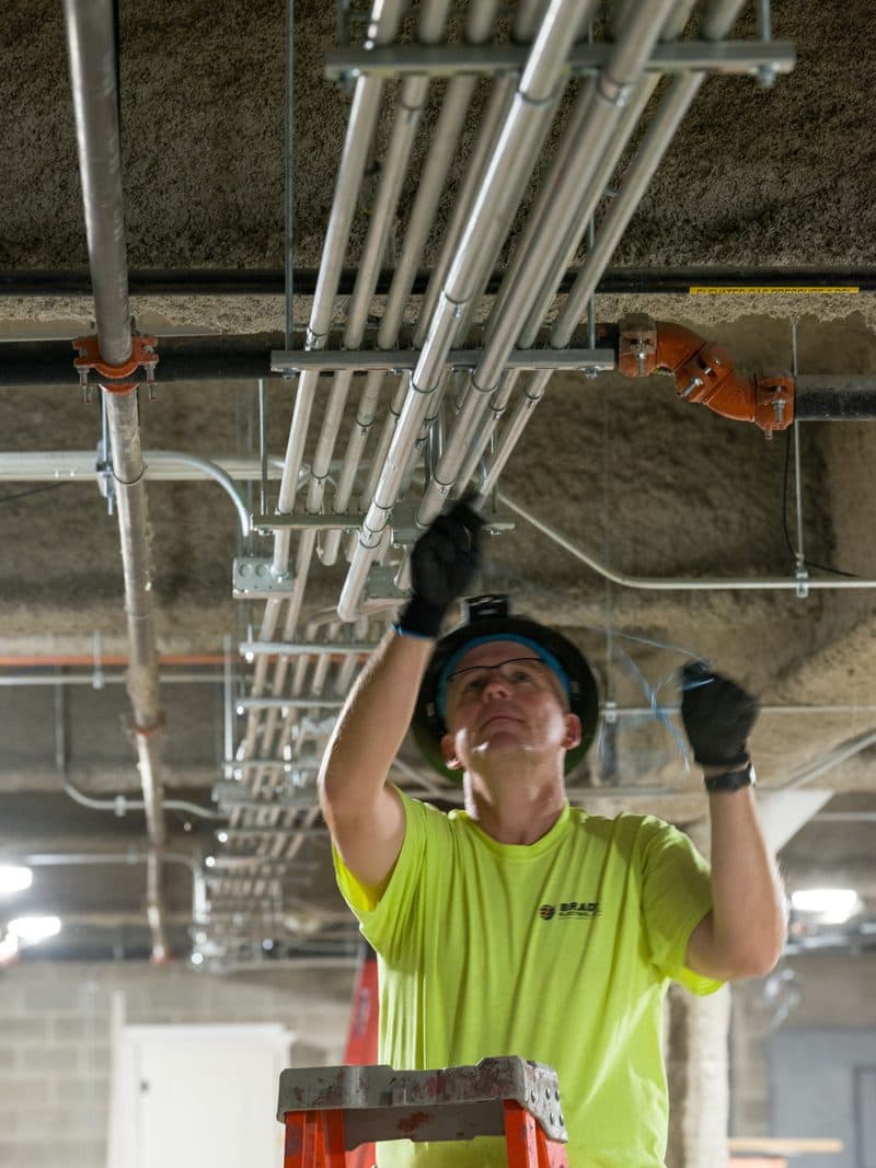 Brady electrician working overhead on conduit