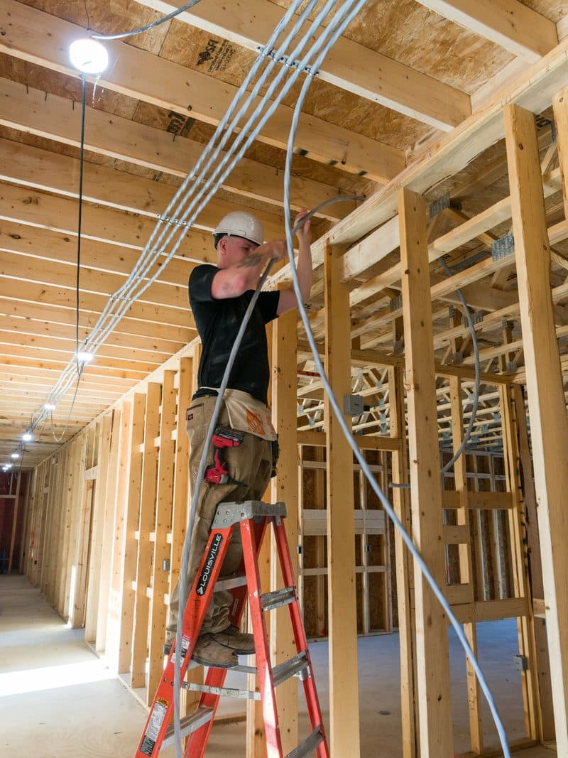 Brady electrician on ladder wiring a new build corridor