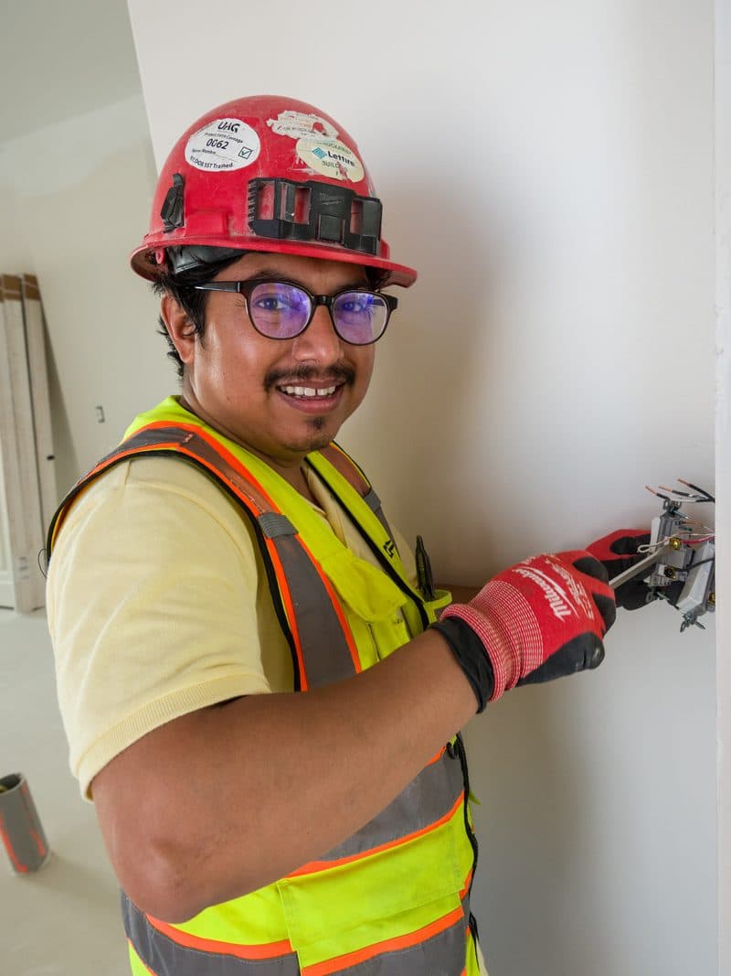 Brady electrician smiling at camera while installing outlet