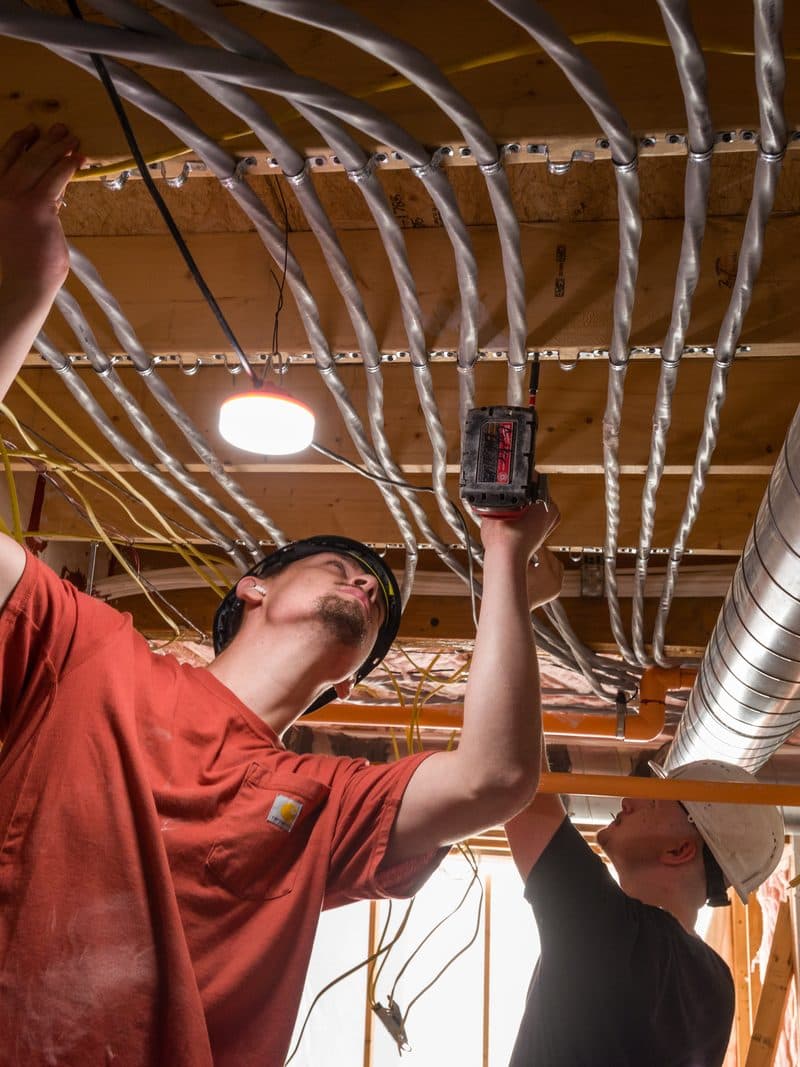 Two Brady electricians working together on ceiling conduit